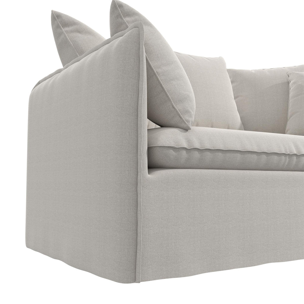 The Collette Slipcover Loveseat Sofa is a modern, light grey loveseat with clean lines and minimalist design. It offers plush cushions, soft fabric, and high-density foam seating for comfort and support. A close-up showcases its side/backrest adorned with pillows.