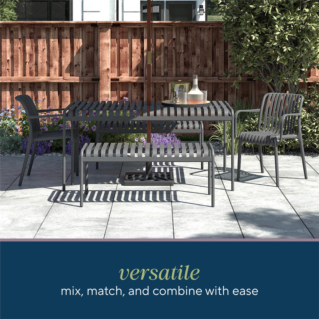 Modern metal outdoor patio scene with Bennett Stacking Dining Chairs (Set of 4), a table, and bench. A wooden fence and greenery are in the background. Text reads, Versatile: mix, match, and combine with ease. Durable resin design requires no assembly as shadows play on the paved patio.