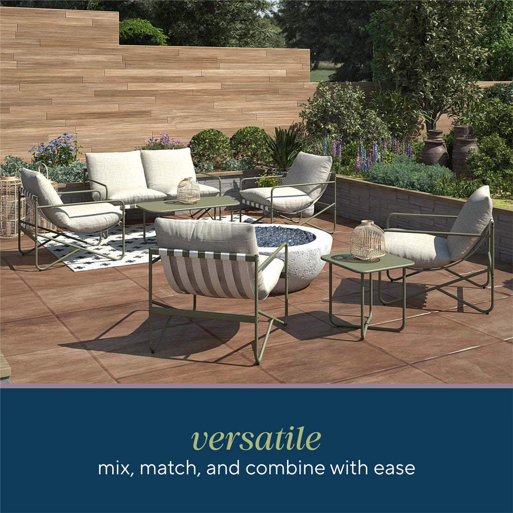 An outdoor patio features the modern Wrenn 4-Piece Sling and Cushion Conversation Set around a round fire pit on a large tile floor, perfect for gatherings. It includes a wooden privacy wall and lush greenery. Text reads: “Versatile, mix, match, and combine with ease.”.