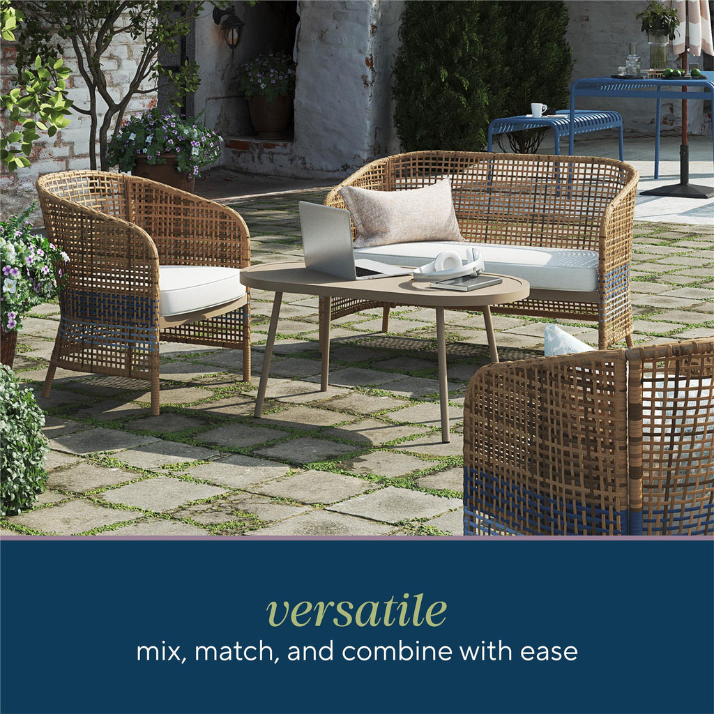 The outdoor space showcases the Ava 4-Piece Wicker Conversation Set in French blue, including chairs, a loveseat, and a coffee table. A laptop and teacup sit on the table atop a paved patio surrounded by greenery. Text reads versatile mix, match, and combine with ease.